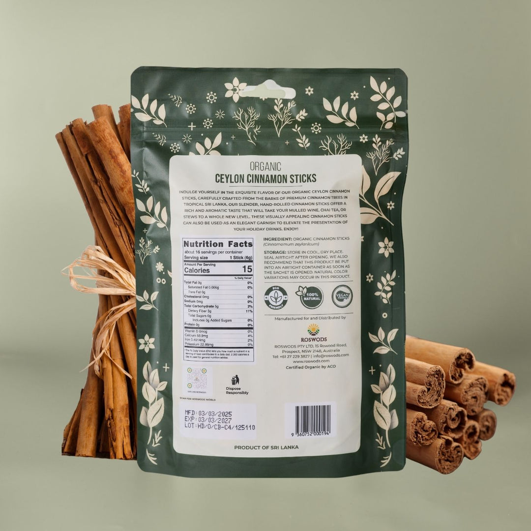 Back of Roswods Organic Ceylon Cinnamon Sticks bag showing Nutrition Facts panel, ingredients (Organic Cinnamon Sticks - Cinnamomum zeylanicum), storage instructions, and Eco Friendly, 100% Natural, and Vegan Natural badges. Product of Sri Lanka. Bag displayed against a sage green background with loose cinnamon sticks.